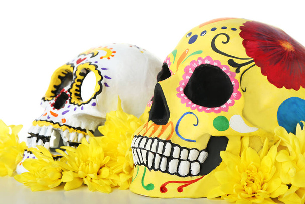 Geschilderde menselijke schedels voor Mexico 's Dag van de Doden (El Dia de Muertos) en bloemen op witte achtergrond - Foto, afbeelding