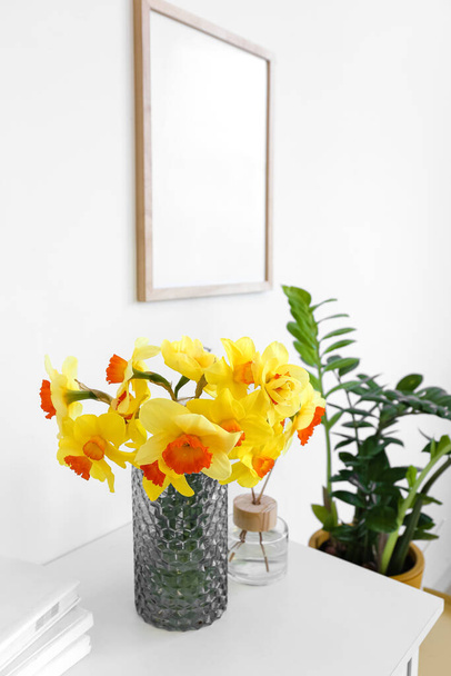 Vase mit Narzissenblüten auf dem Tisch im Zimmer - Foto, Bild