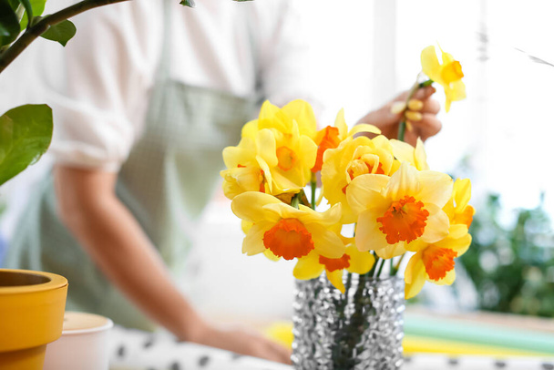 Vase with narcissus flowers on table in flower workshop - 写真・画像