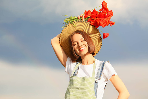 Beautiful female farmer with bouquet of poppy flowers in field - Zdjęcie, obraz