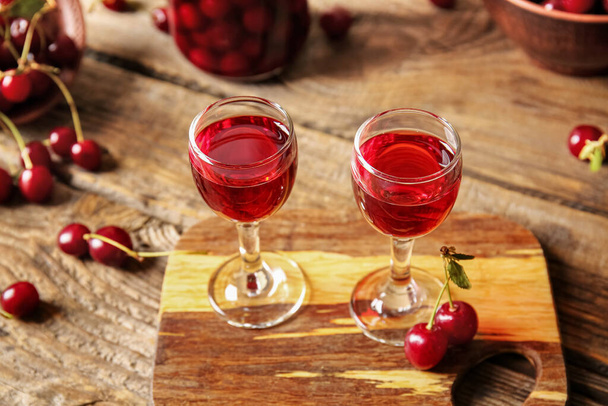 Glasses of sweet cherry wine on wooden background - Foto, Bild