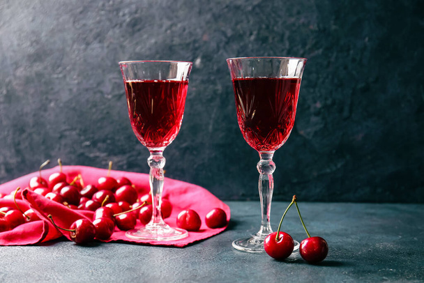 Glasses of sweet cherry wine on dark background - Valokuva, kuva