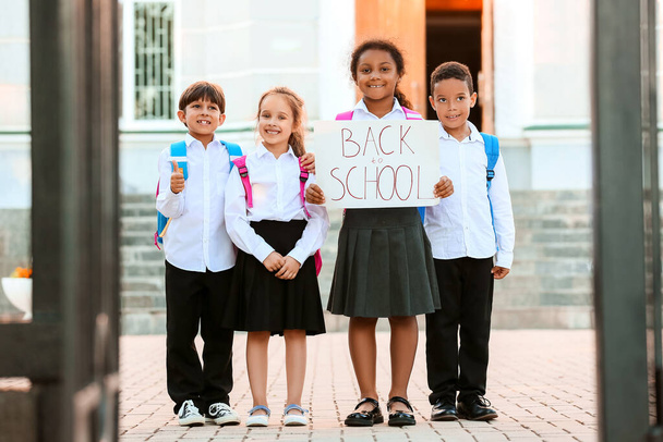 Cute małe dzieci gospodarstwa plakat z tekstem z powrotem do SCHOOOL zewnątrz - Zdjęcie, obraz