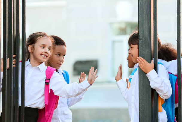 Χαριτωμένοι μικροί μαθητές κοντά στην είσοδο του σχολείου - Φωτογραφία, εικόνα