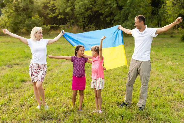 Flag Ukraine in hands of little girl in field. Child carries fluttering blue and yellow flag of Ukraine against background field. - Fotoğraf, Görsel
