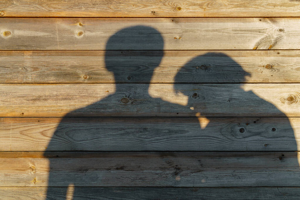 Varjo mies ja nainen maalaismainen puinen seinä aurinkoinen ilta - Valokuva, kuva