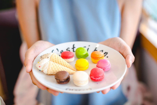 Mix color of macaroon on wihte plate with french language holding on girl hand in blue - Fotoğraf, Görsel