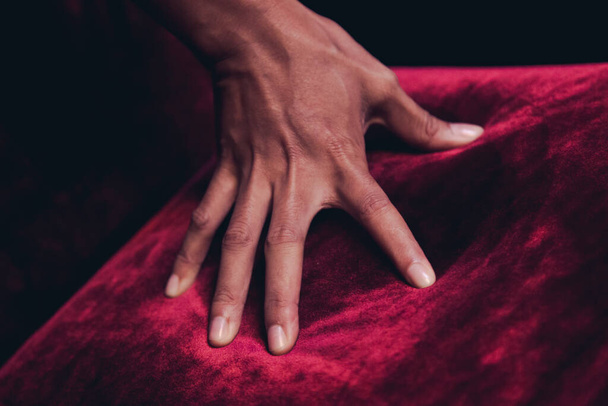 Черная кожа руки касаясь красной ковровой дорожки меха на стуле сделать некоторые ярко-красный свет - Фото, изображение