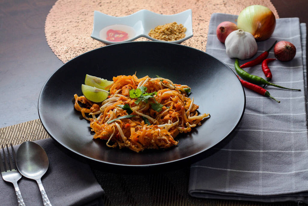 Thajské jídlo Pad thajské (thajské národní jídlo) Pad thajské na černém talíři s vápnem a koření. - Fotografie, Obrázek