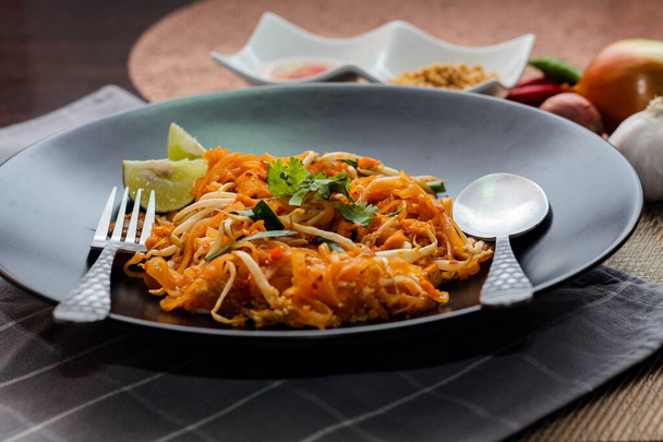 Ταϊλανδικό Food Pad Thai (ταϊλανδέζικο εθνικό πιάτο) Pad Thai σε μαύρο πιάτο με ασβέστη και καρυκεύματα. - Φωτογραφία, εικόνα