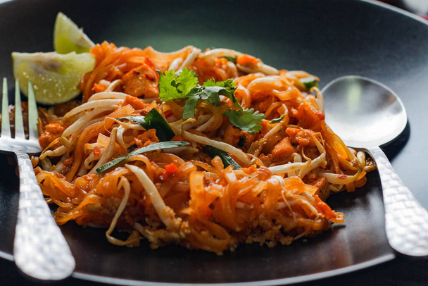 Ταϊλανδικό Food Pad Thai (ταϊλανδέζικο εθνικό πιάτο) Pad Thai σε μαύρο πιάτο με ασβέστη και καρυκεύματα. - Φωτογραφία, εικόνα