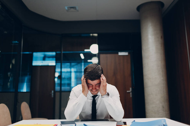 Сумний бізнесмен сидить за офісним столом. Ділові люди в кризі та депресії після концепції пандемії ковідо-19
 - Фото, зображення