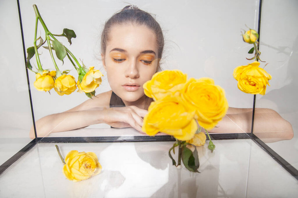Female model behind glass box with flowers - Zdjęcie, obraz