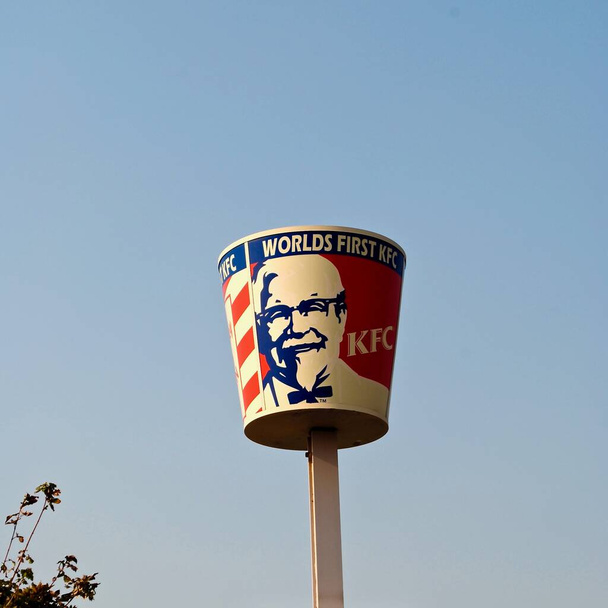 Salt Lake City, Utah, ABD: Dünyanın ilk Kentucky Fried Chicken veya KFC. Devasa dönen, kırmızı, beyaz, mavi tavuk kovası üzerinde Albay Sanders 'ın resmi olan "Dünyalar Önce KFC" yazıyor.. - Fotoğraf, Görsel