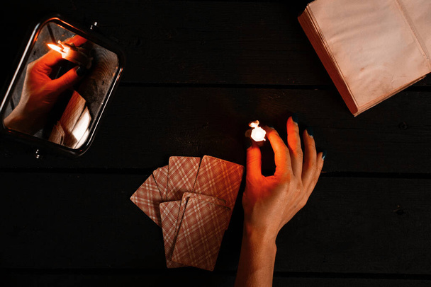 una vela encendida fue llevada por espejos y las tarjetas de adivinación yacen cerca, adivinación en tarjetas a la luz de las velas en una mesa negra, magia, brujería y brujería - Foto, Imagen