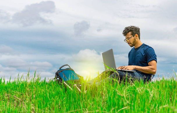 Jovem de óculos trabalhando em seu laptop, homem no campo com seu computador - Foto, Imagem
