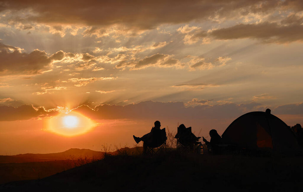 Zonsondergang kijken in rose vallei zonsondergang (kizil vadi) met silhouet van toeristen en mensen zitten in picknickstoelen en in de buurt van campingtent - Foto, afbeelding