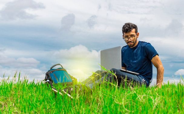 Jovem de óculos trabalhando em seu laptop, homem no campo com seu computador - Foto, Imagem