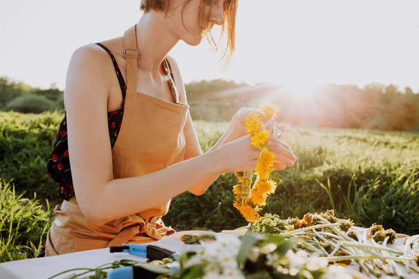 Florist workshop. Pretty woman making wreath from dandelions. Romantic background of florist at work - Foto, immagini