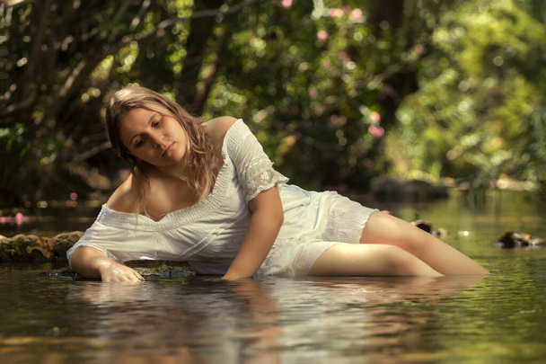 Beautiful young woman with white dress near stream of water. - Foto, Imagem