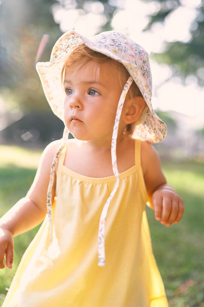 Little girl in a panama hat and a dress looks thoughtfully into the distance. Portrait - Foto, afbeelding
