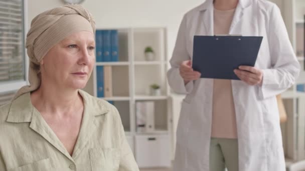 Orta ölçekli, onkolojiden acı çeken orta yaşlı bir kadının röntgen sonuçları elinde olan kadın doktordan kötü haberler alırken orta ölçekli görüntüsü. - Video, Çekim