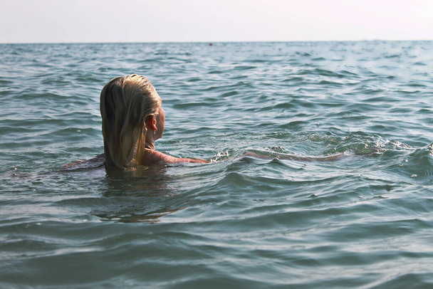 The girl in the sea looks at the horizon - Fotó, kép