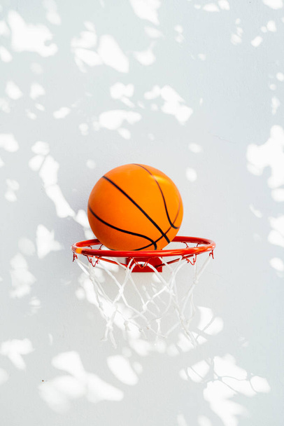 Basketball hoop on a white wall. The ball about to enter the ring. - Photo, Image