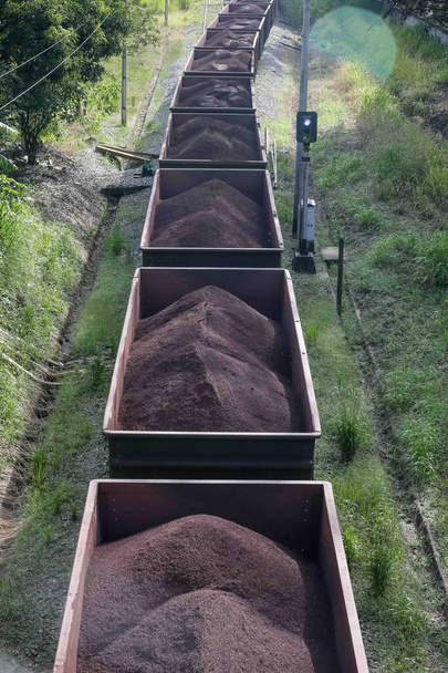 Widok pociągu towarowego MRS poruszającego się po mieście z kontenerami załadowanymi rudą żelaza. - Zdjęcie, obraz