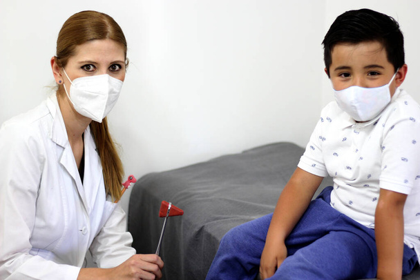 Female pediatrician doctor examining a 7-year-old Latino boy in her office - 写真・画像