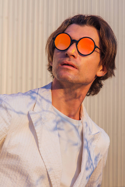 Close up portrait of a handsome man with round hippie sunglasses during sunset - 写真・画像