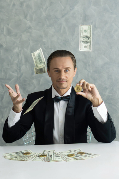 Homme d'affaires riche commerçant tenant Bitcoin pièce d'or pour les entreprises Bitcoin trader échanger de nouvelles devises et billets de banque billet de dollar américain sur le concept d'entreprise de la table - Photo, image