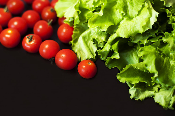 зеленый салат и помидоры черри на темном фоне - Фото, изображение