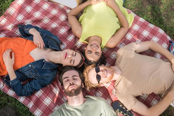 Young people lying with closed eyes on plaid - Fotoğraf, Görsel