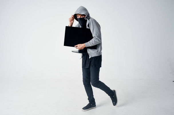 un uomo in maschera un ladro con un monitor tra le mani crimine - Foto, immagini