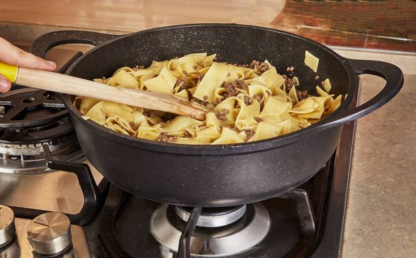 Roer in spaghetti met gemalen rundvlees, gebakken in spaghetti bolognese pan volgens recept van het internet - Foto, afbeelding