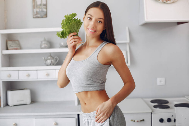 Beautiful and sporty girl in a kitchen with a vegetables - Φωτογραφία, εικόνα