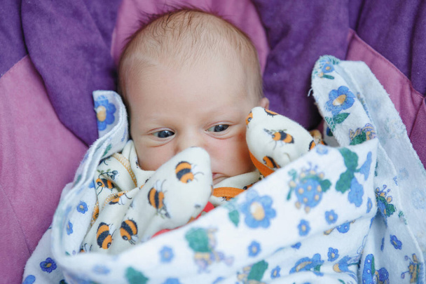 Portrait of a blue-eyed newborn baby girl lies and looks at the camera. Happy childhood. Parental care. - Photo, Image