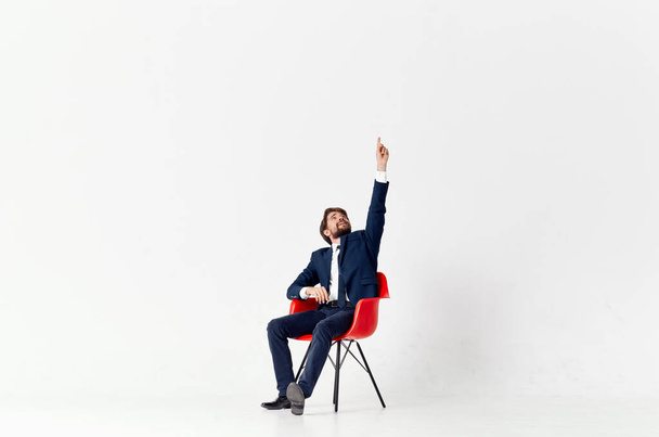 mężczyzna w garnitur czerwony krzesło praca biuro lekkie tło - Zdjęcie, obraz