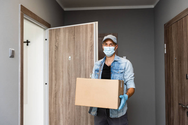 Domácí dodávka nákupní box muž nosí rukavice a ochranné masky doručuje balíčky na dveře - Fotografie, Obrázek