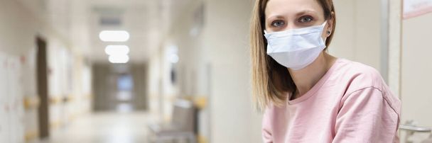 Портрет жінки в захисній медичній масці сидить в лікарняному коридорі
 - Фото, зображення