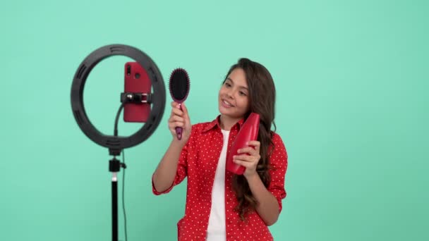 lachende kind schoonheid blogger aanwezig shampoo tegen haaruitval tonen kam, product voorstel. - Video