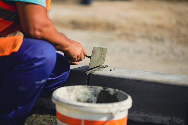 Bir inşaat sahasında kaldırım kenarını sağlamlaştıran bir işçiyle sığ alan derinliği (seçici odak) görüntüsü. - Fotoğraf, Görsel
