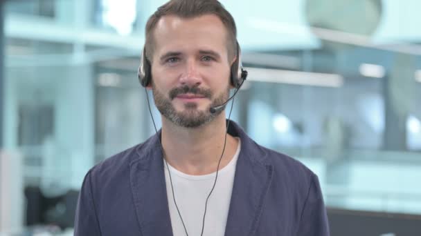 Középkorú üzletember fejhallgatóval mosolygós kamera  - Felvétel, videó