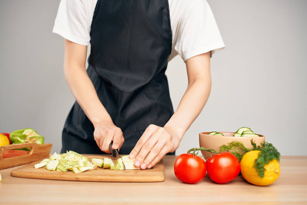Woman in black apron cutting vegetables housework cooking - Foto, Bild