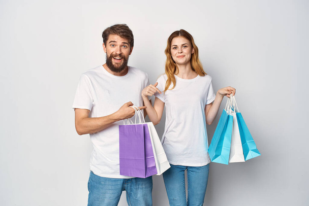 mladý pár v bílém trička s taškami v ruce nakupování zábava - Fotografie, Obrázek