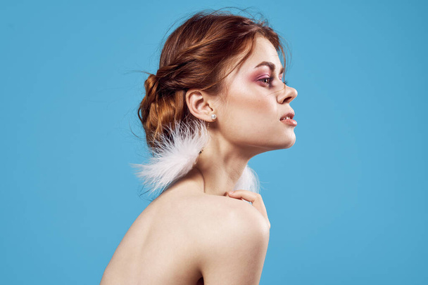 žena s holými rameny nadýchané náušnice jasný make-up modré pozadí - Fotografie, Obrázek