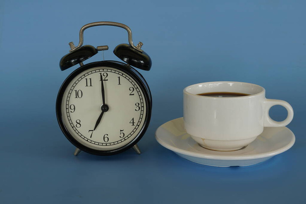 despertador y una taza de café sobre fondo azul - Foto, Imagen
