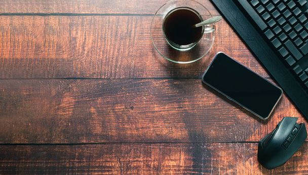 Coffee mug, smartphone, keyboard, mouse at the desk. - Photo, image