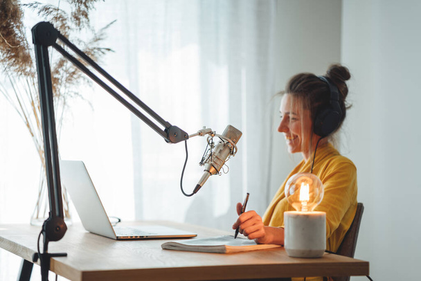Gospodyni radiowa nagrywa i nadaje podcast z domowej roboty studia. Kobieta rozmawiać do mikrofonu na stole - Zdjęcie, obraz
